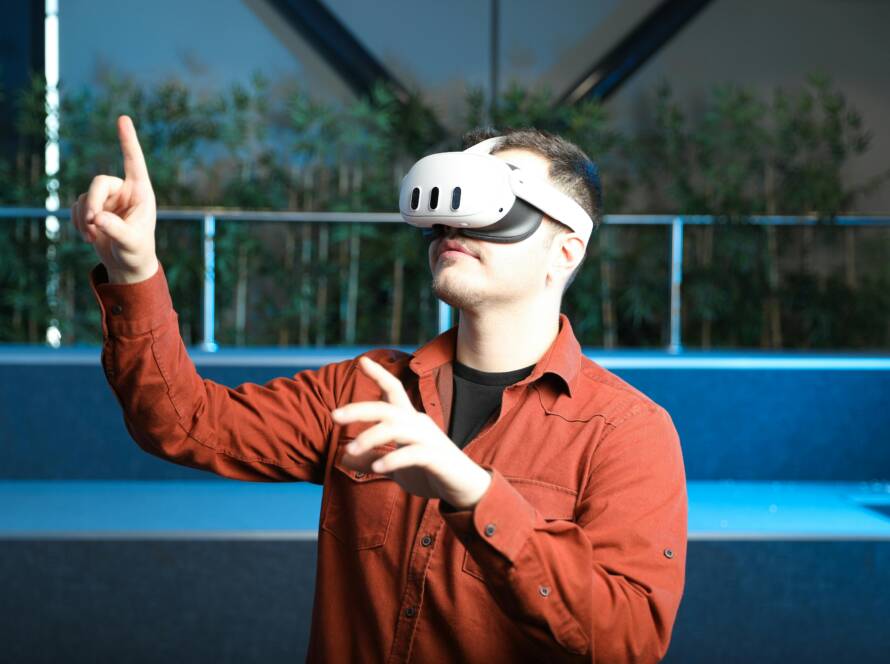 A man wearing a VR headset interacts with augmented reality indoors.